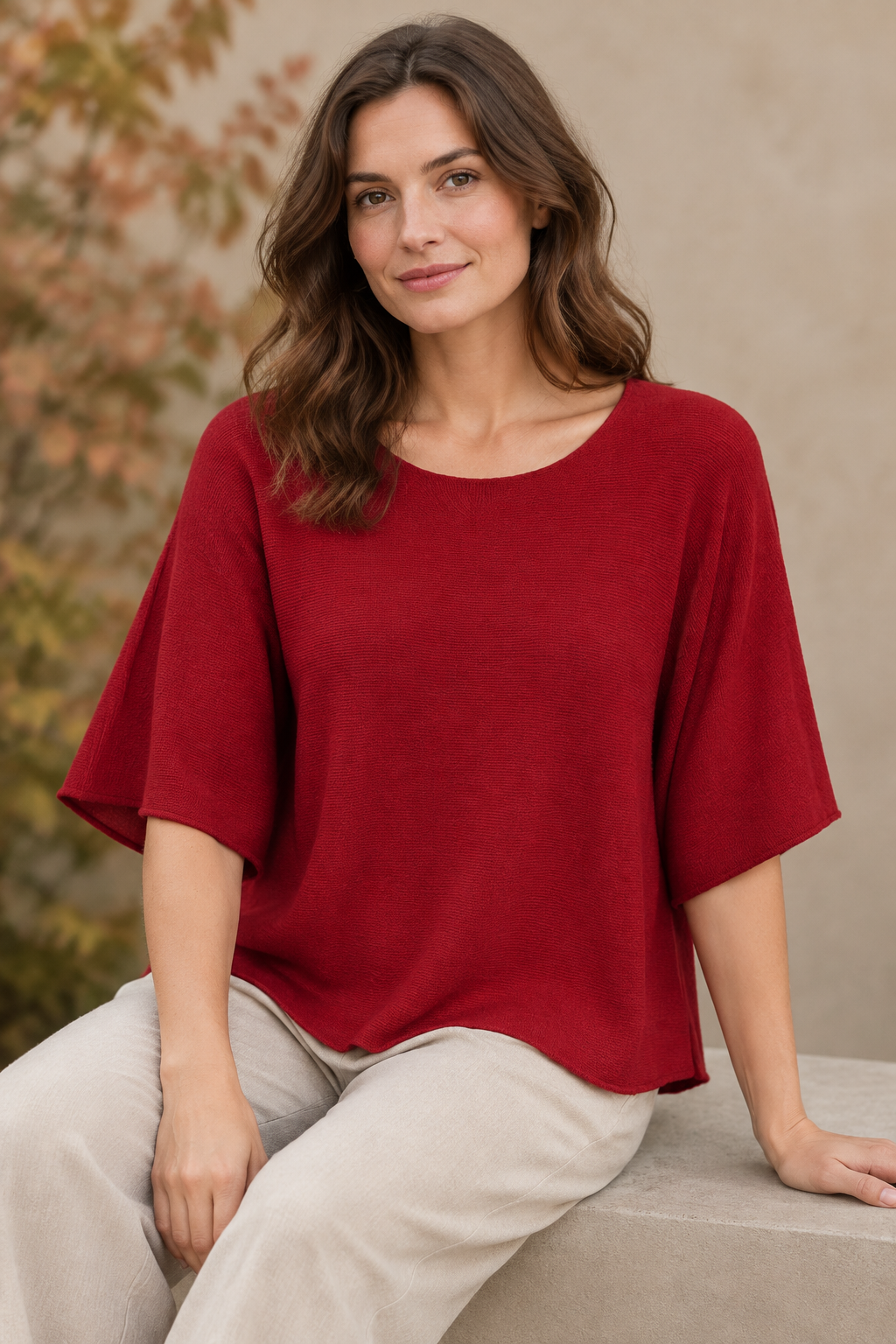 Rotes Strickoberteil am sitzenden Modell