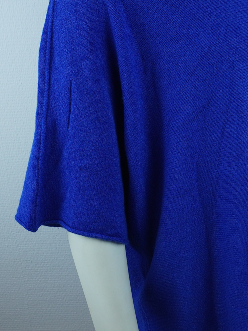 Nahaufnahme des blauen Strickoberteils: weiter Ärmel mit sichtbarer Naht und Stoffstruktur