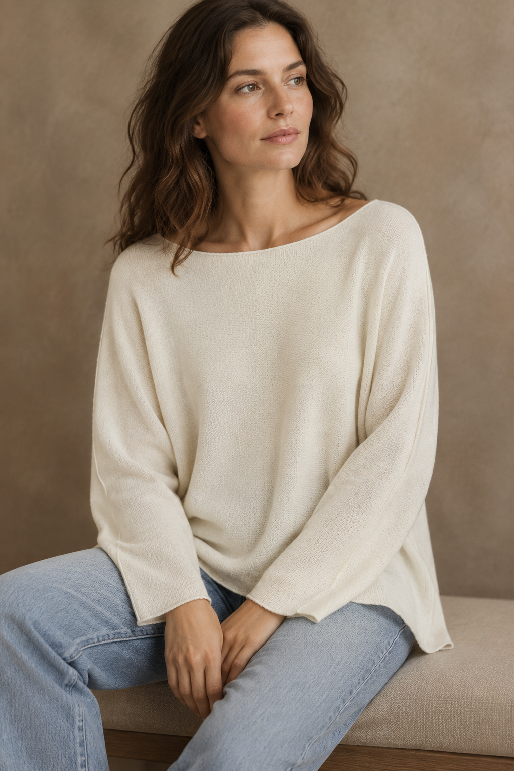 Cremeweißes Langarm-Strickoberteil am sitzenden Modell