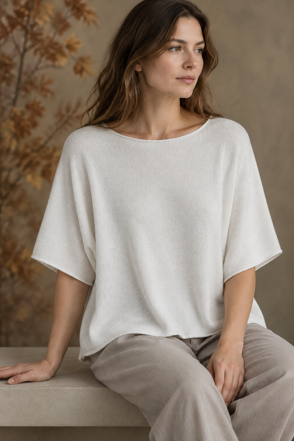 Weißes Strickoberteil am sitzenden Modell