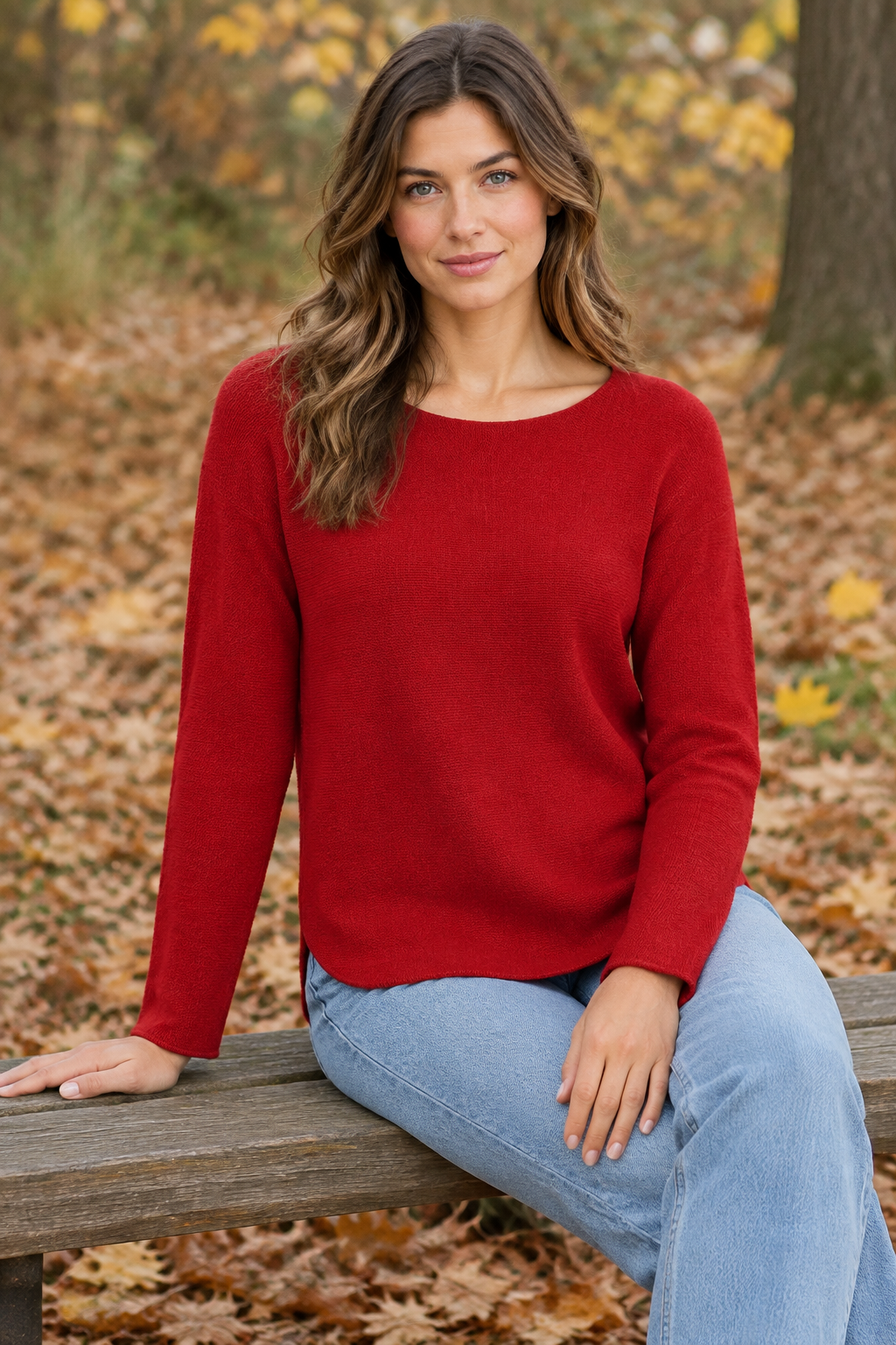 Rotes Langarm-Strickoberteil am sitzenden Modell auf Herbstbank