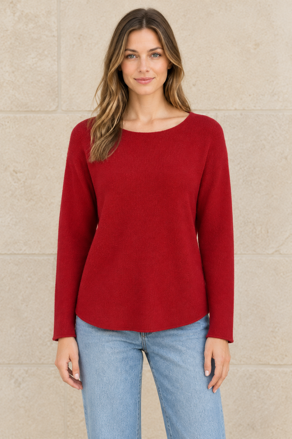 Rotes Langarm-Strickoberteil am Modell vor heller Steinwand