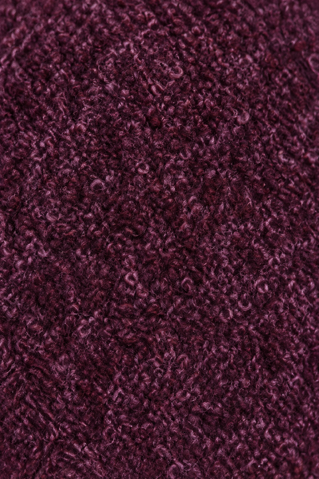Nahaufnahme der bordeauxroten Bouclé-Struktur des Wintermantels