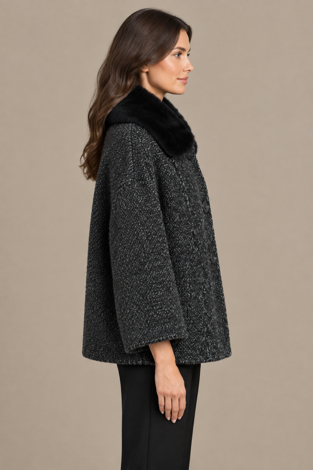 Dunkelgrauer Bouclé-Wintermantel mit schwarzem Fellkragen seitlich am Model