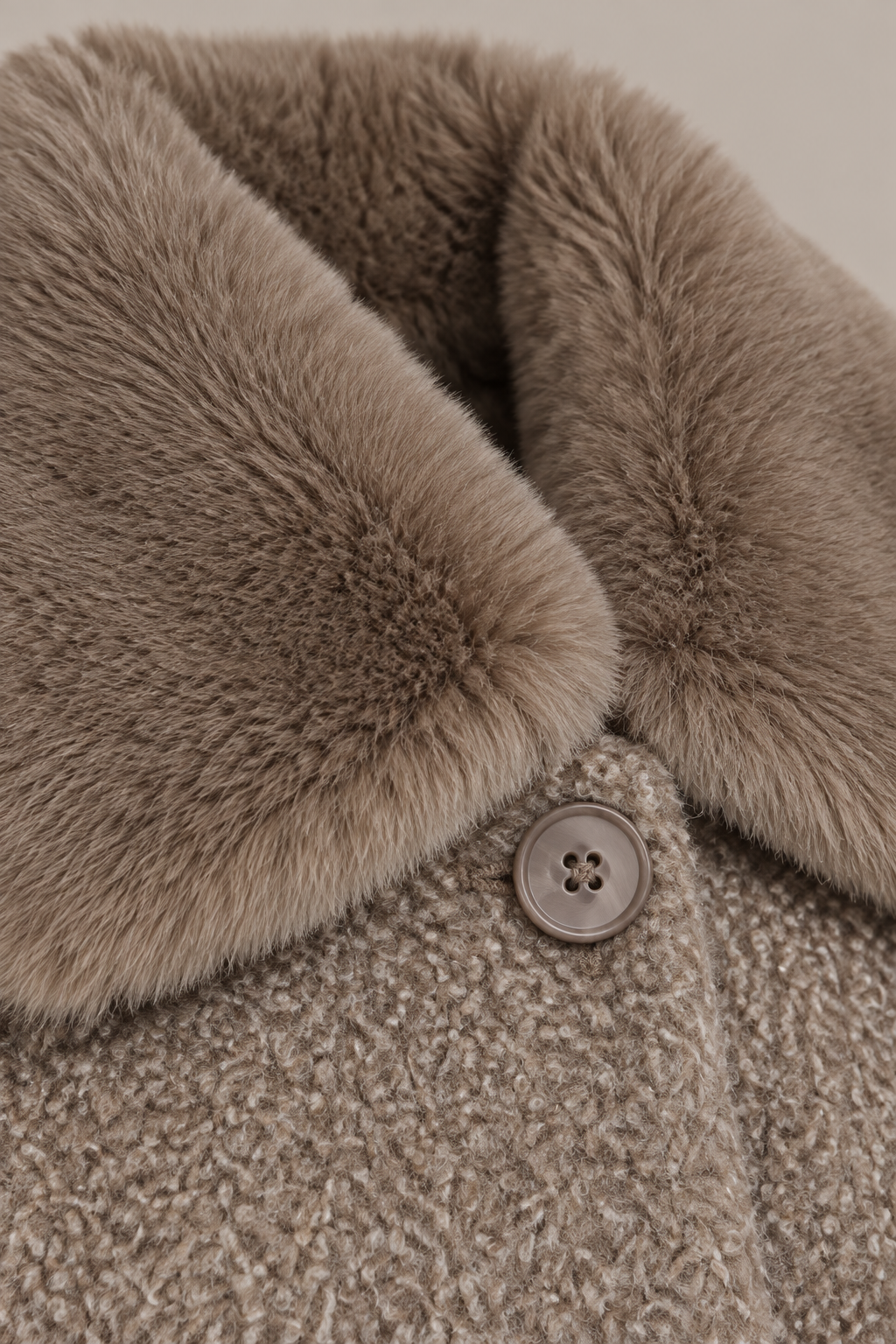 Nahaufnahme des weichen teddybeigen Fellkragens am Bouclé-Wintermantel